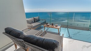 Ein Balkon mit einer Couch, Stühlen und einem Tisch mit Blick aufs Meer.