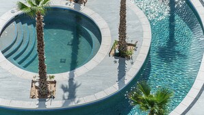 Ein kreisförmiger Pool mit einer Insel in der Mitte und umliegenden Palmen.