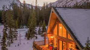 A cabin with a deck, stone foundation, and a view of snow-covered mountains. - Cozy Cabin • Hot Tub • Mtn Views • Firepit • Near Breck (Fairplay)