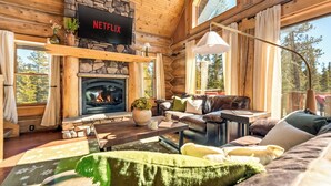 A log cabin interior with a stone fireplace, a Netflix TV, and a cozy seating area. - Cozy Cabin • Hot Tub • Mtn Views • Firepit • Near Breck (Fairplay)