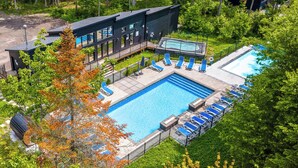 A modern building with a swimming pool, sun loungers, and a garden area. - Private Spa - Nature Chalet & Resort near Quebec City (Pont-Rouge)