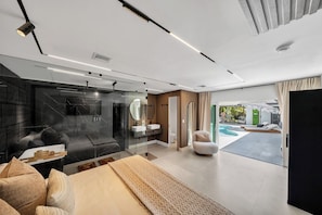 Camera moderna con un letto grande, cabina doccia in vetro e vista su area piscina esterna.