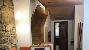 A cozy living area with a stone wall, wooden staircase, and a bench with cushions. - CA LA ROSITA Charming house in Solsona, Ideal for families or couples. (Solsona)