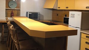 A kitchen with a central island, bar stools, a refrigerator, a microwave, and hanging pendant lights. - CA LA ROSITA Charming house in Solsona, Ideal for families or couples. (Solsona)