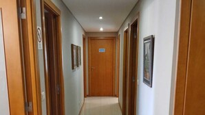 Un couloir avec des portes en bois, une pancarte indiquant « PRIVÉ » et des tableaux encadrés accrochés aux murs.