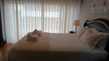 Uma cama bem arrumada com toalhas dobradas, uma luminária de cabeceira e um quadro na parede.