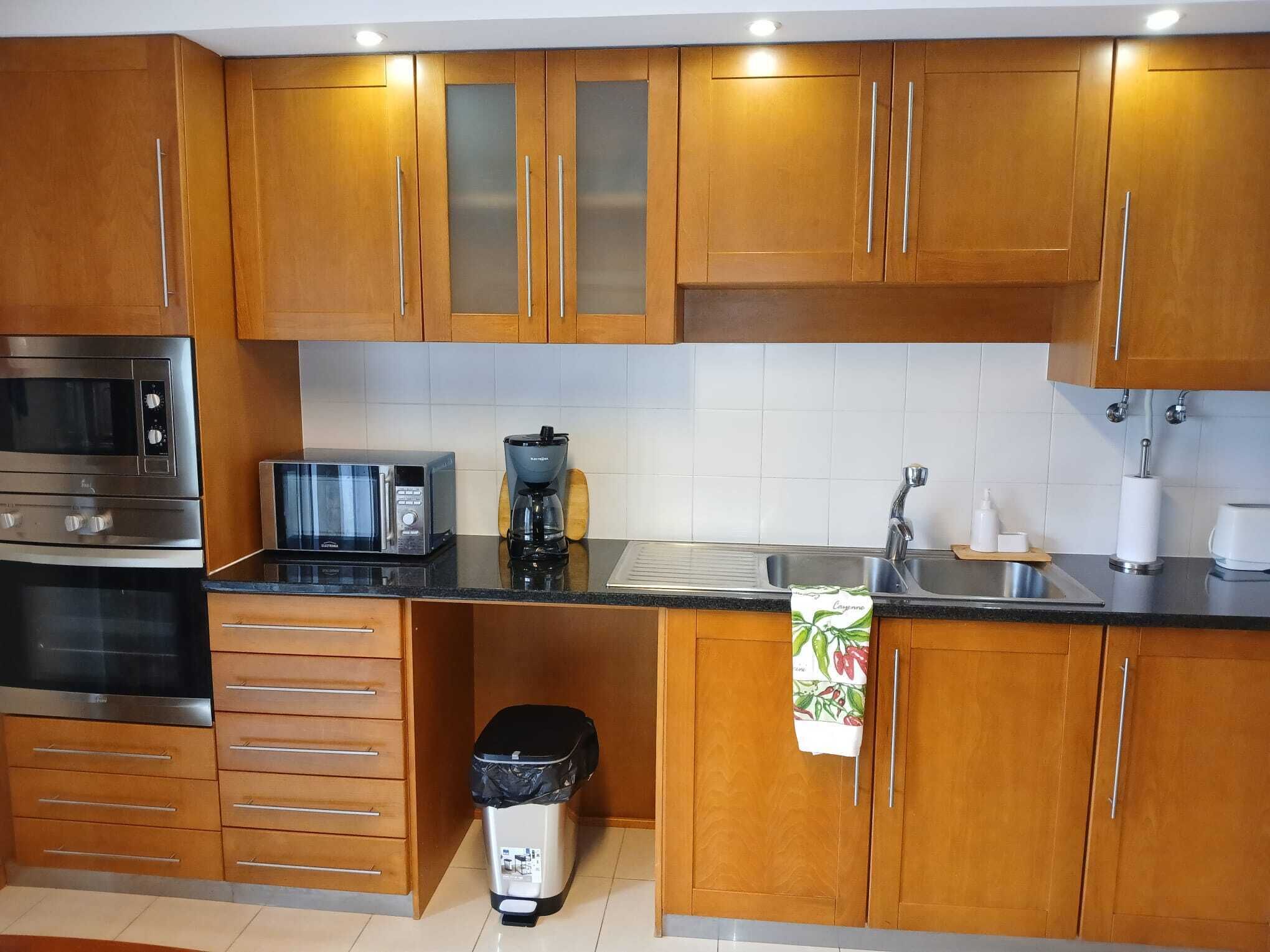 A modern kitchen with wooden cabinets, stainless steel appliances, and a tiled backsplash.