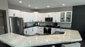 A modern kitchen with white cabinets, stainless steel appliances, and a granite countertop.
