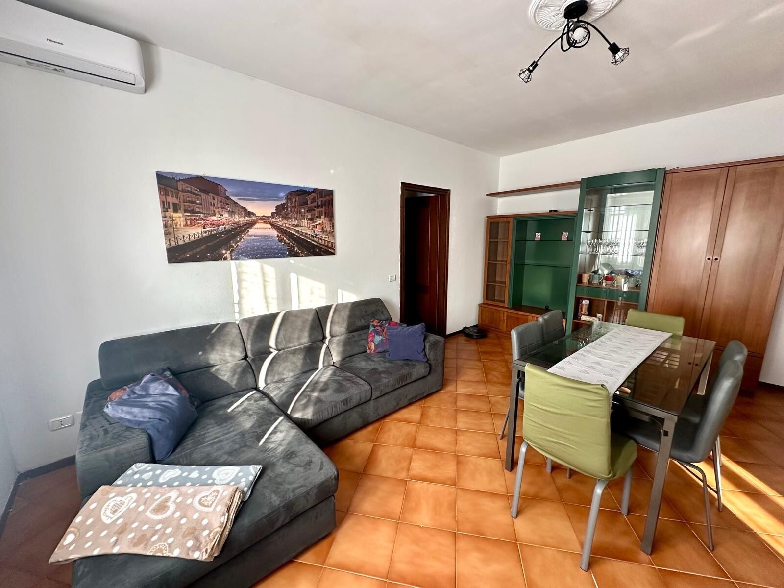 A living room with a sofa, a dining table with chairs, and a kitchen area with cabinets.