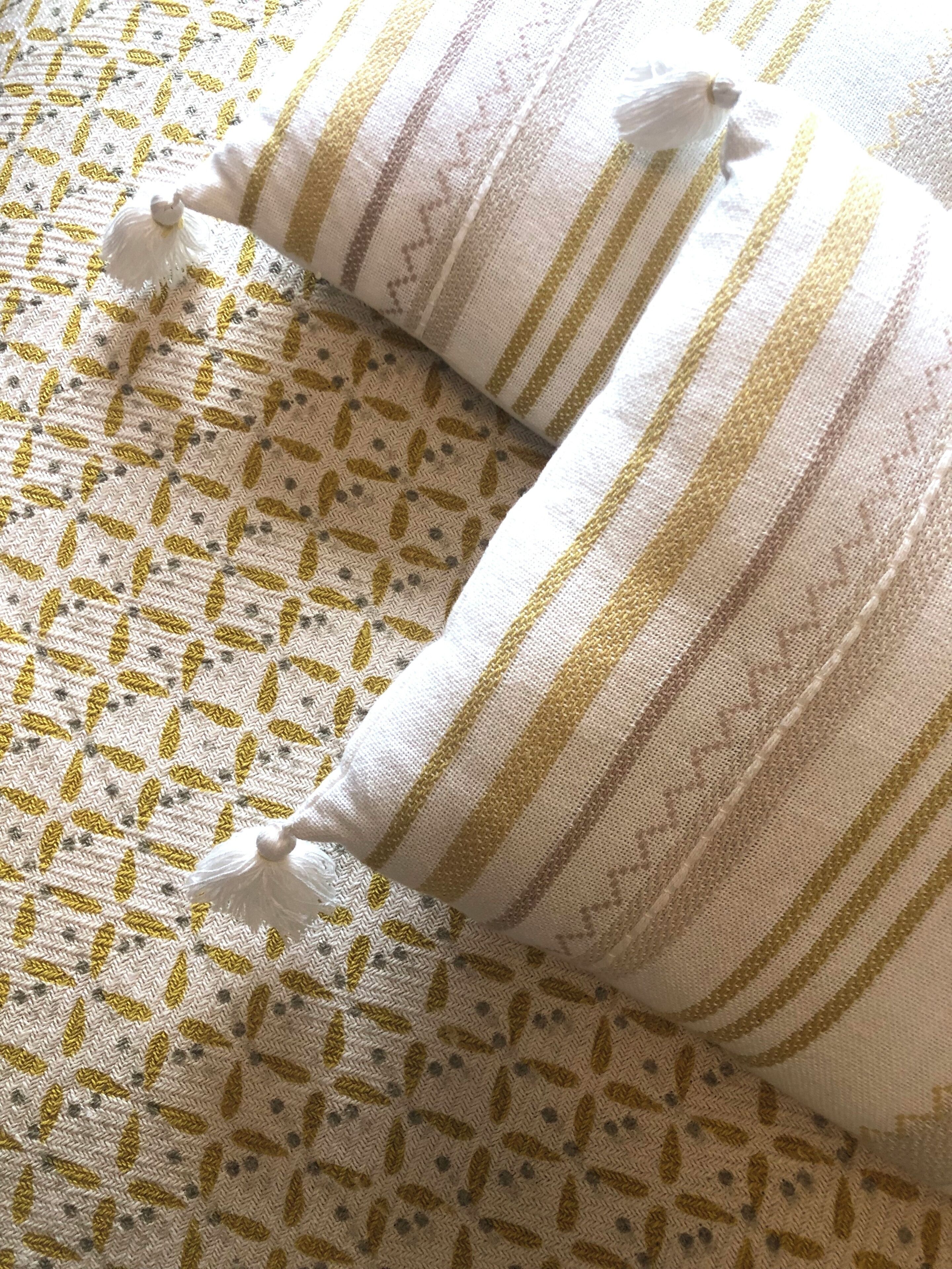 A bed with a patterned bedspread and two pillows with tassels.