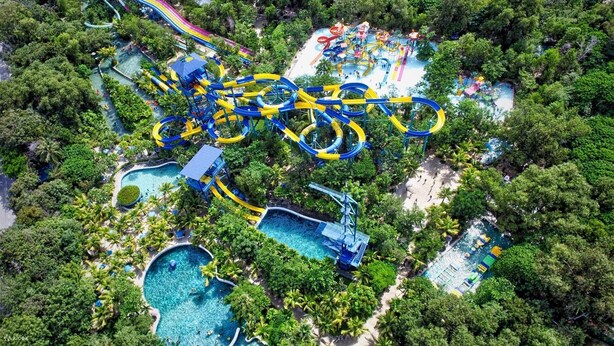 An aerial view of a water park with multiple slides and pools surrounded by dense greenery. - Stylish Cap Cana Apartment • Pool, Gym & Beaches (Punta Cana)