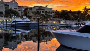 A marina with boats docked, buildings in the background, and a sunset sky. - Stylish Cap Cana Apartment • Pool, Gym & Beaches (Punta Cana)