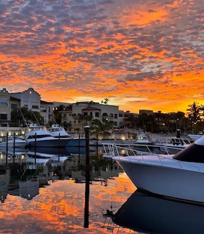 A marina with boats docked, buildings in the background, and a sunset sky. - Stylish Cap Cana Apartment • Pool, Gym & Beaches (Punta Cana)