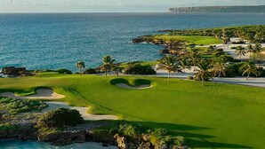 A coastal golf course with a view of the ocean and a distant city skyline. - Resort-Style Golf & Ocean view  Cap Cana (Punta Cana)