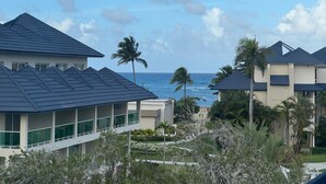 Een resort met meerdere gebouwen, uitzicht op de oceaan en palmbomen.