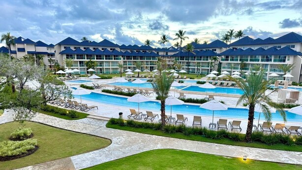 Ett semesterparadis med flera pooler, solstolar och palmer.