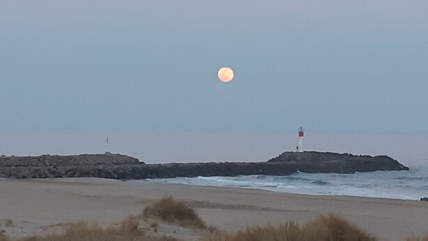 Una platja amb un far situat en un promontori rocos.