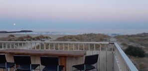 A wooden deck with a table and chairs overlooking a beach with dunes and a lighthouse in the distance. - L'horizon, T3 Sea front, direct access to la roquille beach CAP D'AGDE (CAP D'AGDE)