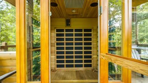 Entrada a una cabaña de madera con puerta de diseño enrejado, una luz en el techo y vistas al exterior.