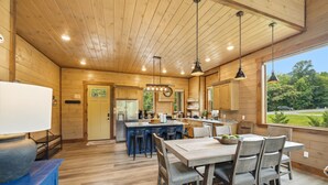 Un interior de madera con cocina, comedor y vistas al exterior.