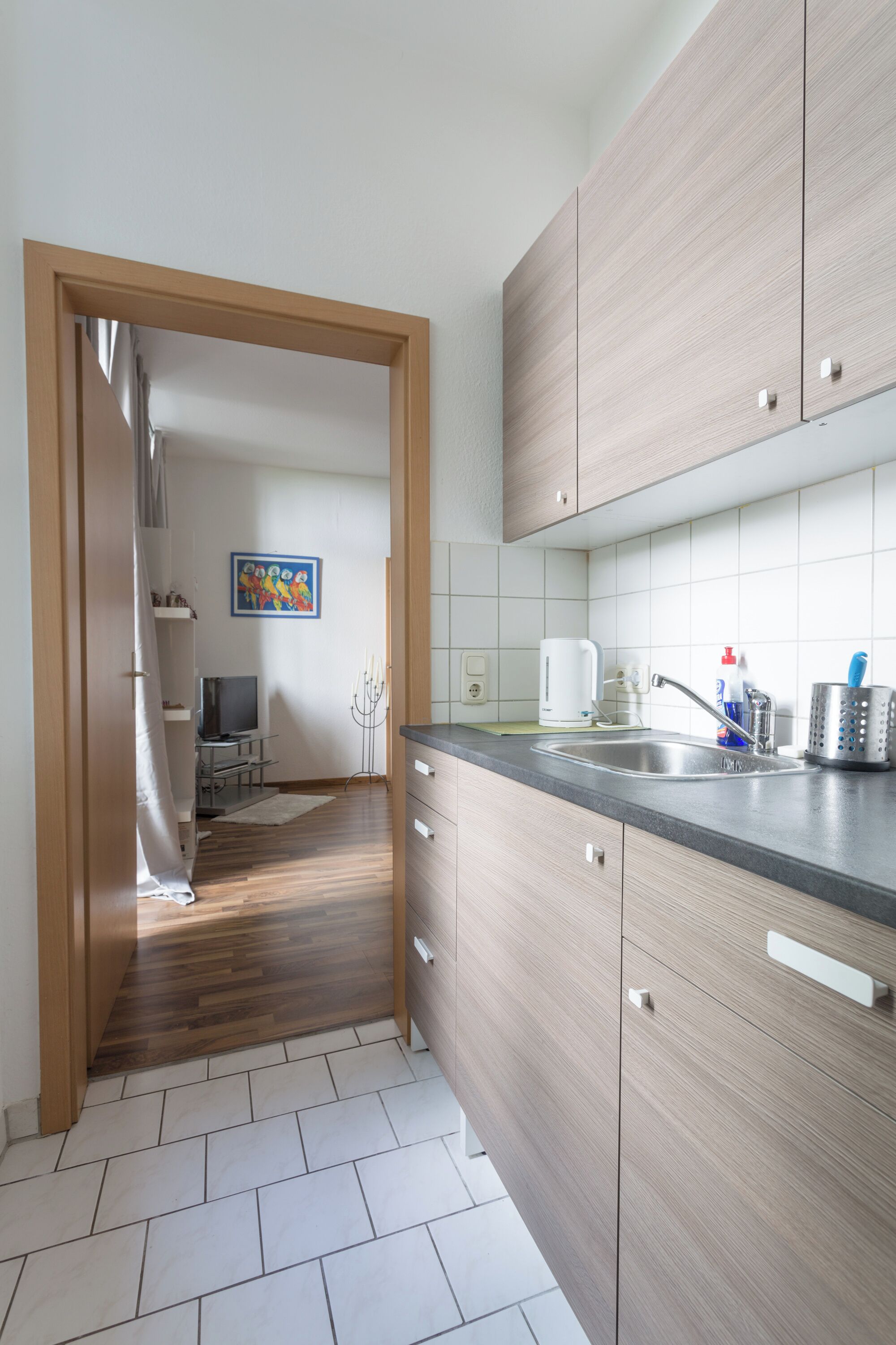 A modern kitchen with wooden cabinets, a stainless steel sink, and a tiled backsplash.