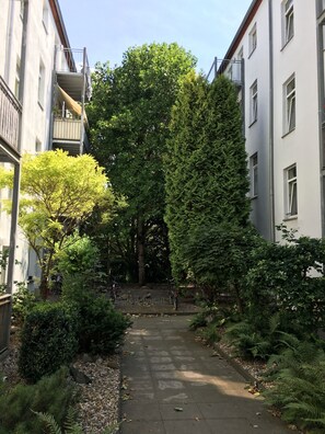A narrow pathway flanked by buildings and dense greenery, with bicycles parked along the path. - Practical apartment for fitters & short stays (Magdeburg)