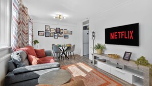 Ein modernes Wohnzimmer mit Sofa, Couchtisch, Fernseher und Kunstwerk an der Wand.