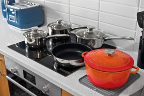 A kitchen with a stove, pots, a toaster, and a red pot on a tray. - Comfy City Base + Free Parking | Walk Everywhere (Belfast)