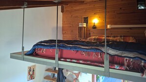 Un lit superposé avec un plafond en bois et un radiateur fixé au mur.