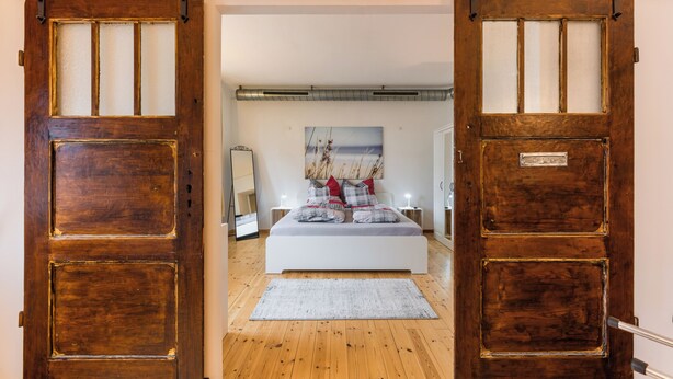 A bedroom with a bed, a nightstand, a mirror, and a painting on the wall. - Spacious ground floor loft with 140 m² - ideal for families & groups of up to 6 (7) people (Magdeburg)