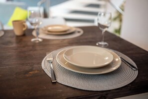 Uma mesa de jantar posta com pratos, talheres e um copo de água.