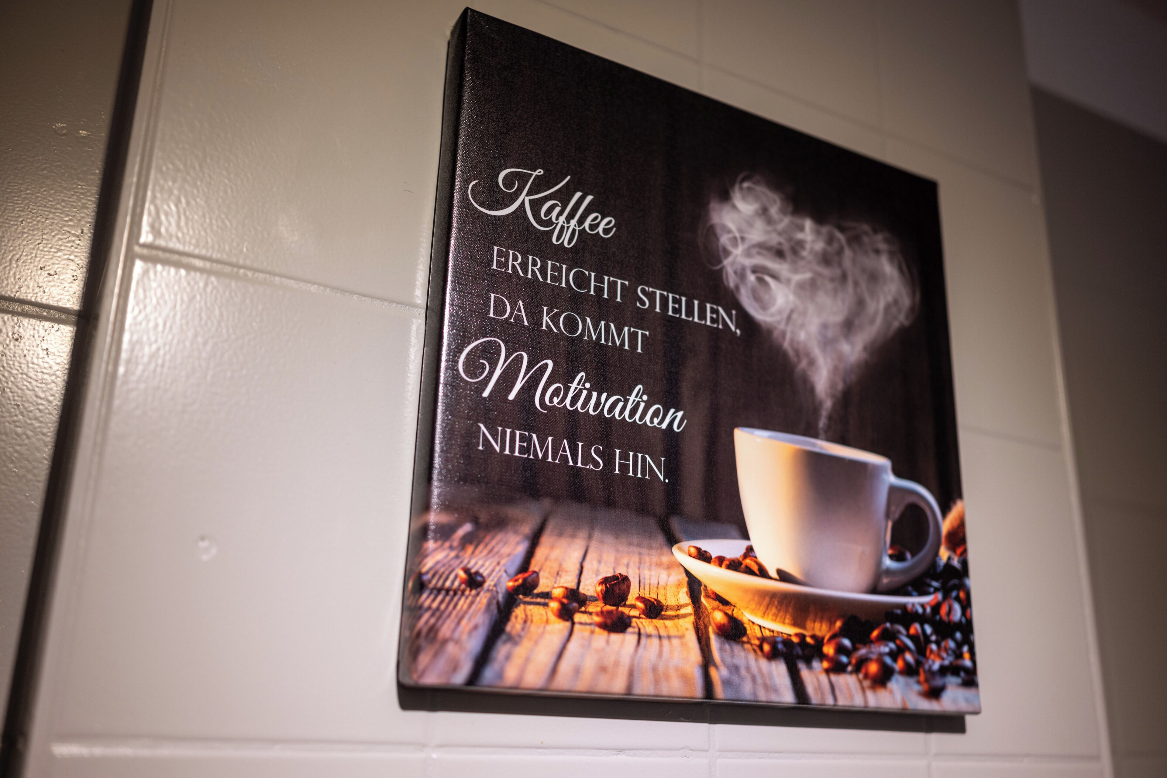 Ein gerahmtes Motivationszitat über Kaffee an der Wand.