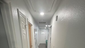 Un pasillo estrecho con paredes blancas y piso de madera.