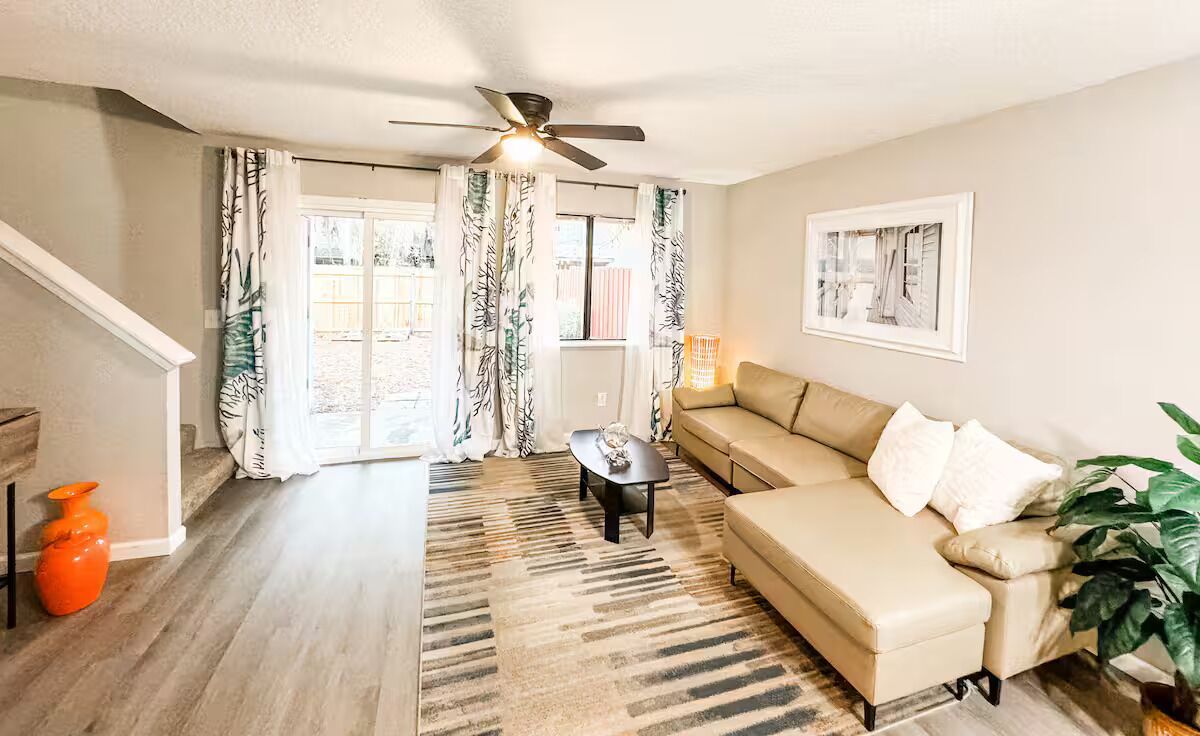A living room with a beige sofa, a coffee table, and a ceiling fan.