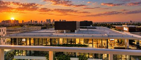 A modern building with multiple floors, large windows, and a rooftop terrace.