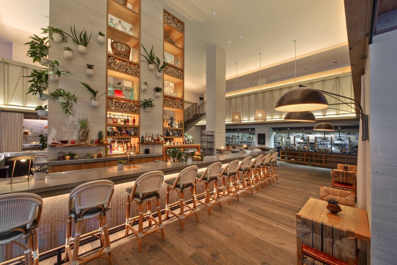 Un grand espace bar doté d’étagères en bois, de chaises en osier et d’un comptoir moderne.
