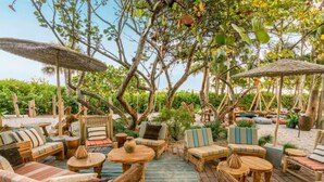 Un espace extérieur aménagé avec du mobilier en bois et des parasols, entouré d’une végétation luxuriante.