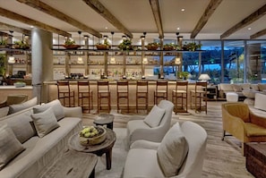 A spacious lounge area with a bar, comfortable seating, and a view of the outdoors. - Stunning Beach Condo with Balcony (Miami Beach)