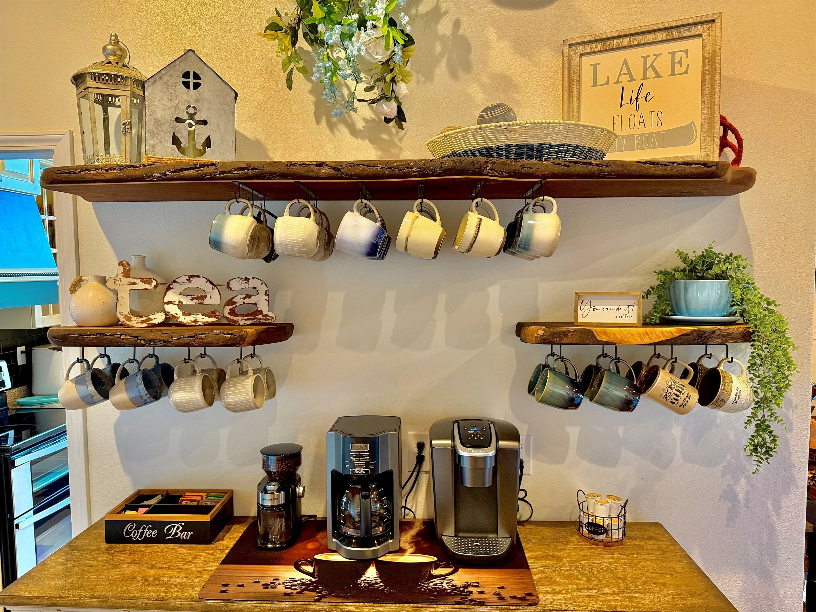 A coffee bar with multiple coffee makers, mugs, and a coffee bar sign.