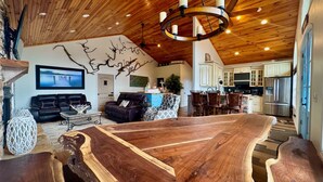 Een ruime woonkamer met een grote houten salontafel, leren banken en een moderne kroonluchter.