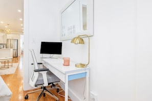 A modern office space with a white desk, a black monitor, a gold desk lamp, and a blue chair.