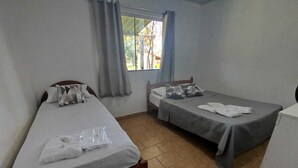 A room with two single beds, a window with curtains, and a white cabinet. - Cantinho das Emerências, a house near the beach in a rustic style with a swimming pool! (Armação dos Búzios)