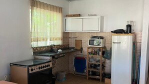 A compact kitchen with a stove, sink, and refrigerator. - Cantinho das Emerências, a house near the beach in a rustic style with a swimming pool! (Armação dos Búzios)