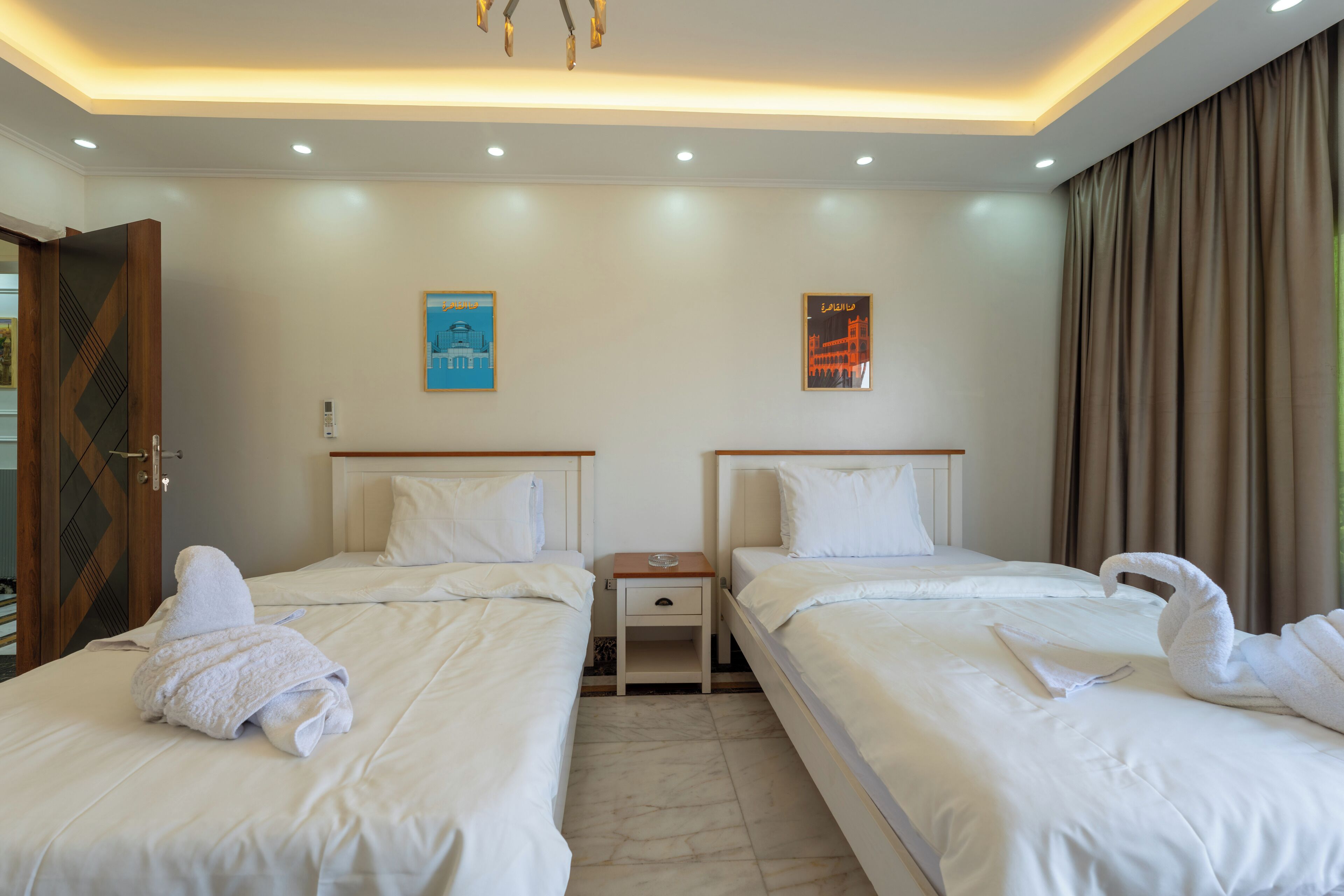 A hotel room with two beds, a nightstand, and a ceiling light fixture.