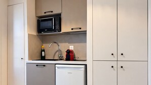 A compact kitchen with a microwave, sink, and a small refrigerator.