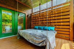 Ein Schlafzimmer mit Bett, einer Hängematte und Blick auf grüne Natur.
