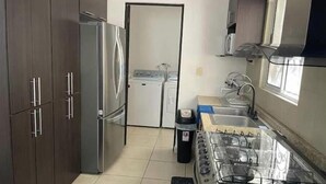A compact kitchen with a refrigerator, washing machine, and a gas stove. - Beautiful entire house near Alameda, Saltillo (Saltillo)