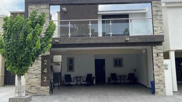 A modern two-story building with a balcony, a covered patio area with seating, and a tree in the foreground. - Beautiful entire house near Alameda, Saltillo (Saltillo)