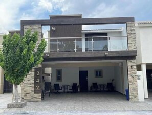 A modern two-story building with a balcony, a covered patio area with seating, and a tree in the foreground. - Beautiful entire house near Alameda, Saltillo (Saltillo)