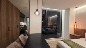 Ein modernes Hotelzimmer mit einem großen Bett, einem Esstisch und einer Küchenzeile.